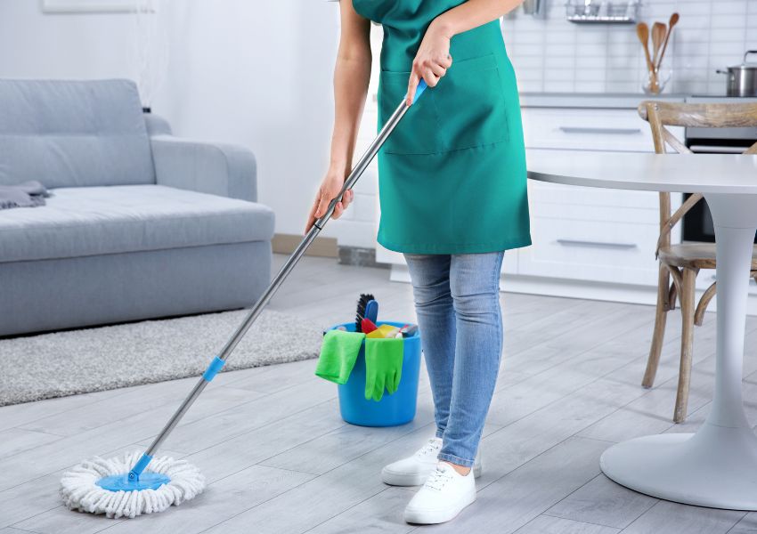A cleaning service takes place in a vacation rental home, where a person mops the floors of a rental.