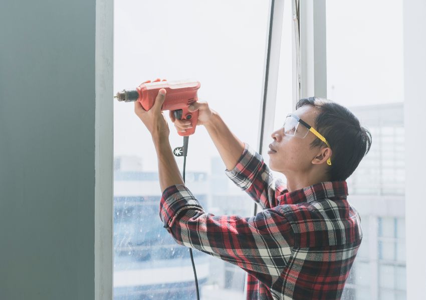 person-using-drill-at-window